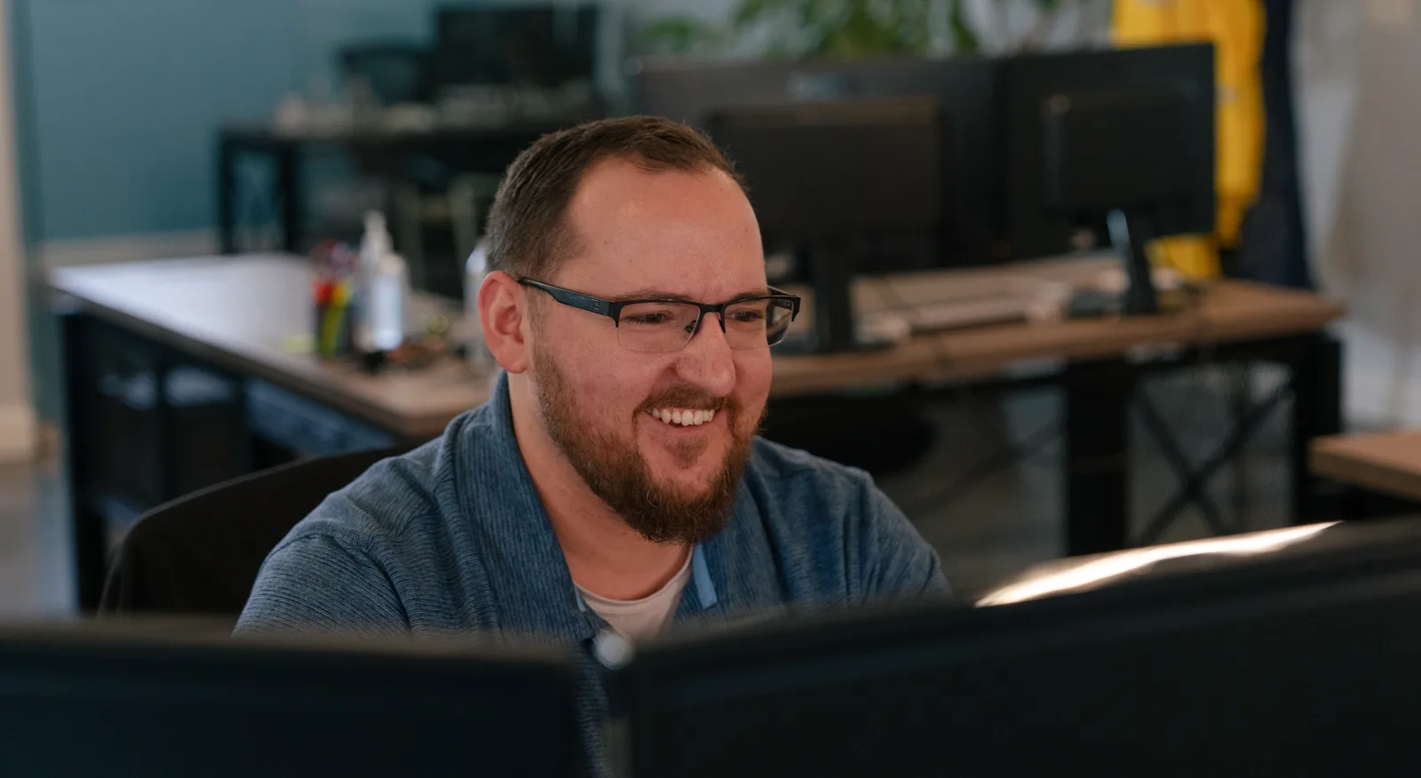 A RoofingSource office teammate smiling at his desk