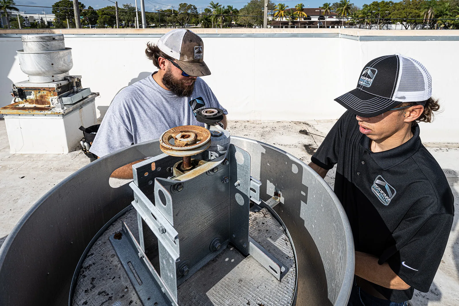 Two RoofingSource teammates servicing an open rooftop grease ventilator