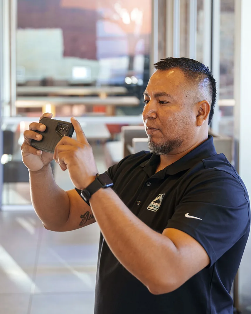 A RoofingSource Field Advisor in a restaurant dining room photographing a leak in the ceiling