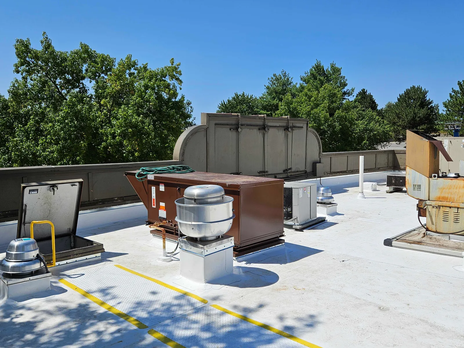 A newly finished white commercial roof membrane with rooftop units and exhaust fans set on it