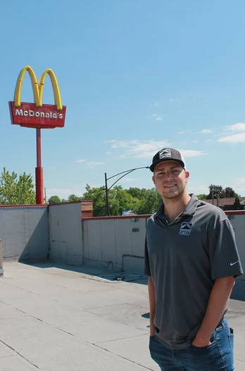 A RoofingSource teammate standing on a restaurant roof, the golden arches sign behind him