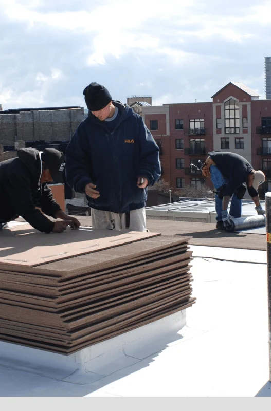 A crew laying insulation boards on a commercial roof deck