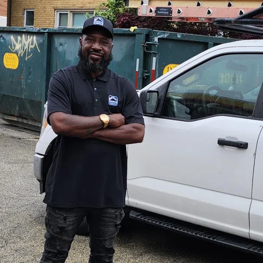 A RoofingSource teammate standing arms crossed beside a company pickup