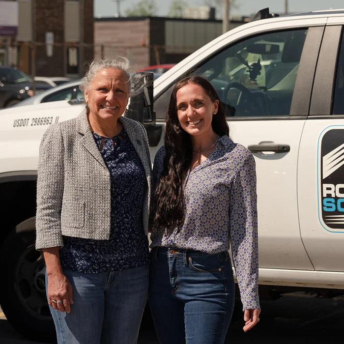 Two RoofingSource teammates beside a service truck