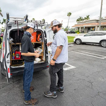 Two RoofingSource teammates working at the open back of a service van