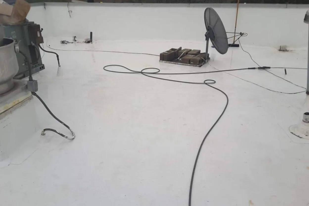 The same corner of the roof clean and white after restoration, dish and cables in place